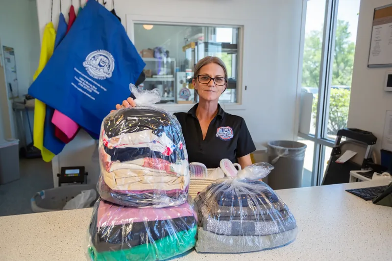Sandy Creek Laundromat employee with professionally folded and packaged pickup and delivery orders