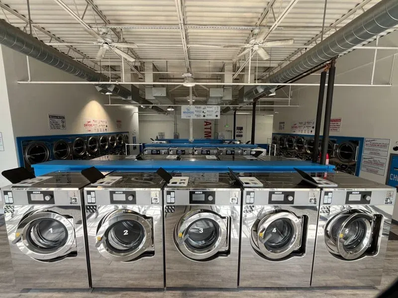 Row of commercial washing machines at Sandy Creek Laundromat Colorado Springs